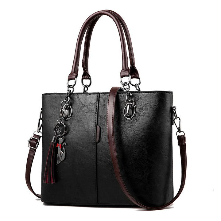 Black leather tote bag, structured, top handles, crossbody strap, tassel charm
