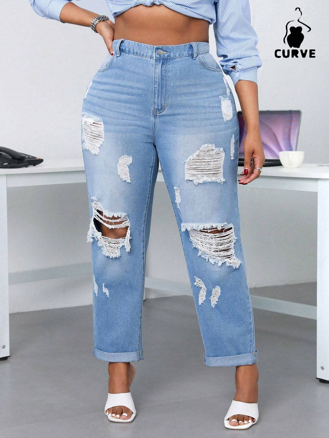 Person wearing ripped blue jeans in an office setting with 'Curve' branding.