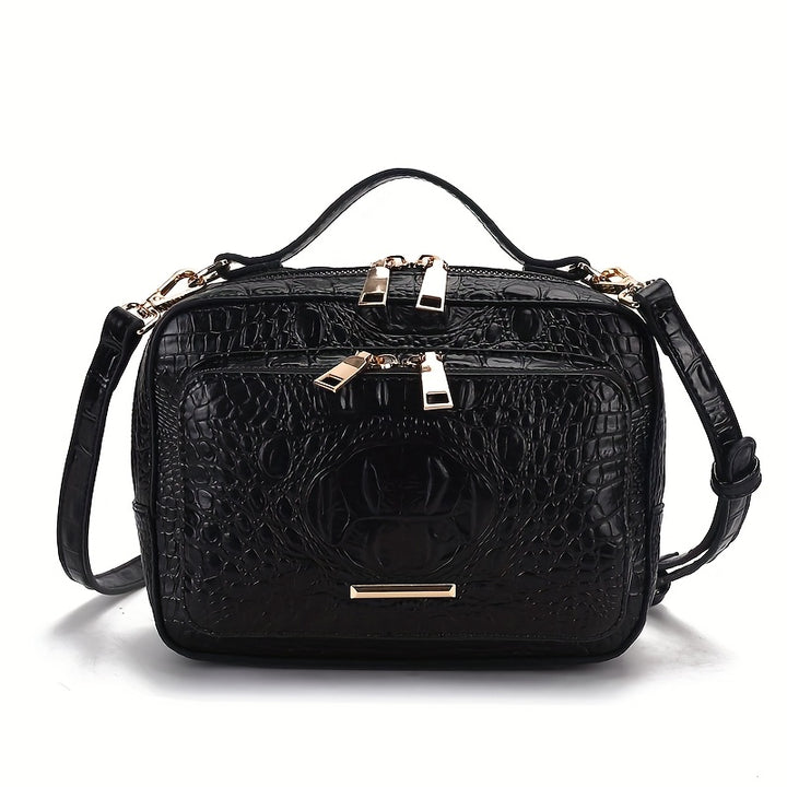 Black crocodile-patterned handbag with gold accents on a white background