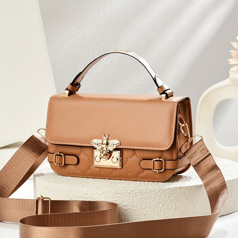 Brown handbag with decorative emblem on a light background