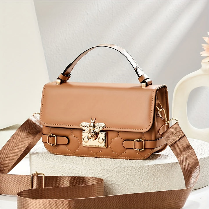 Brown handbag with decorative emblem on a light background
