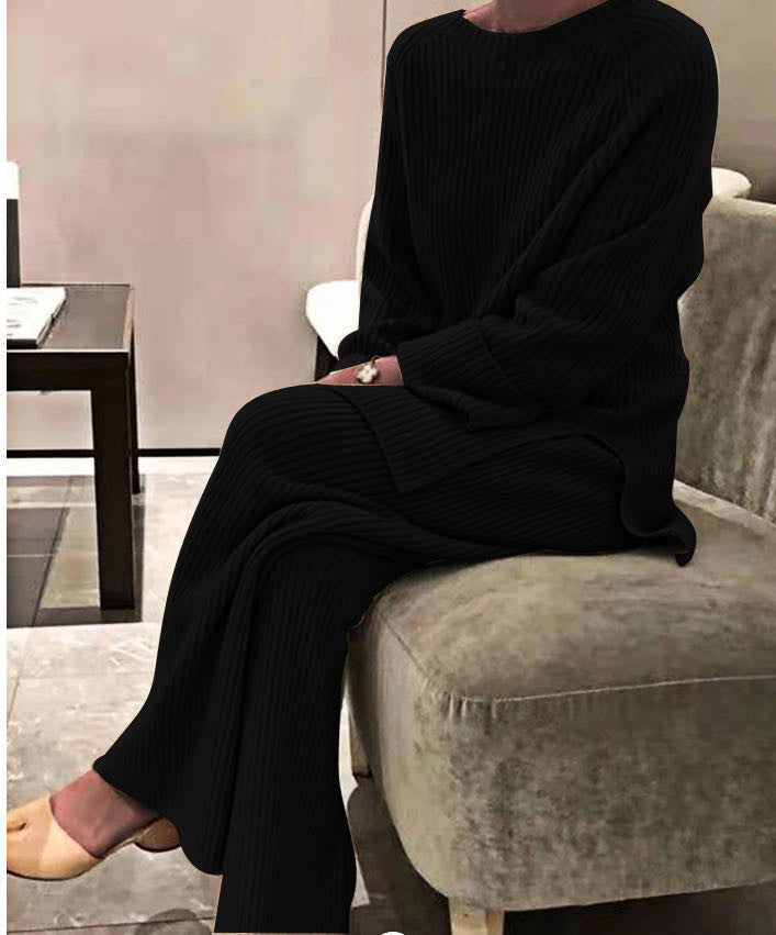 Person wearing a black outfit sitting on a gray chair in an indoor setting.