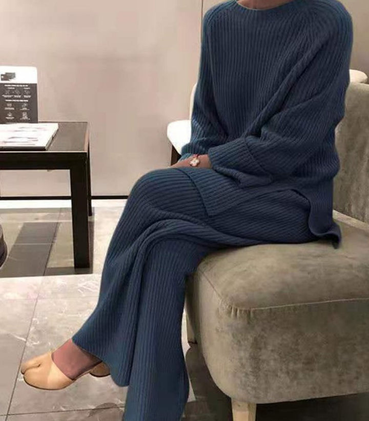 Person wearing a blue ribbed sweater and matching pants sitting on a chair.