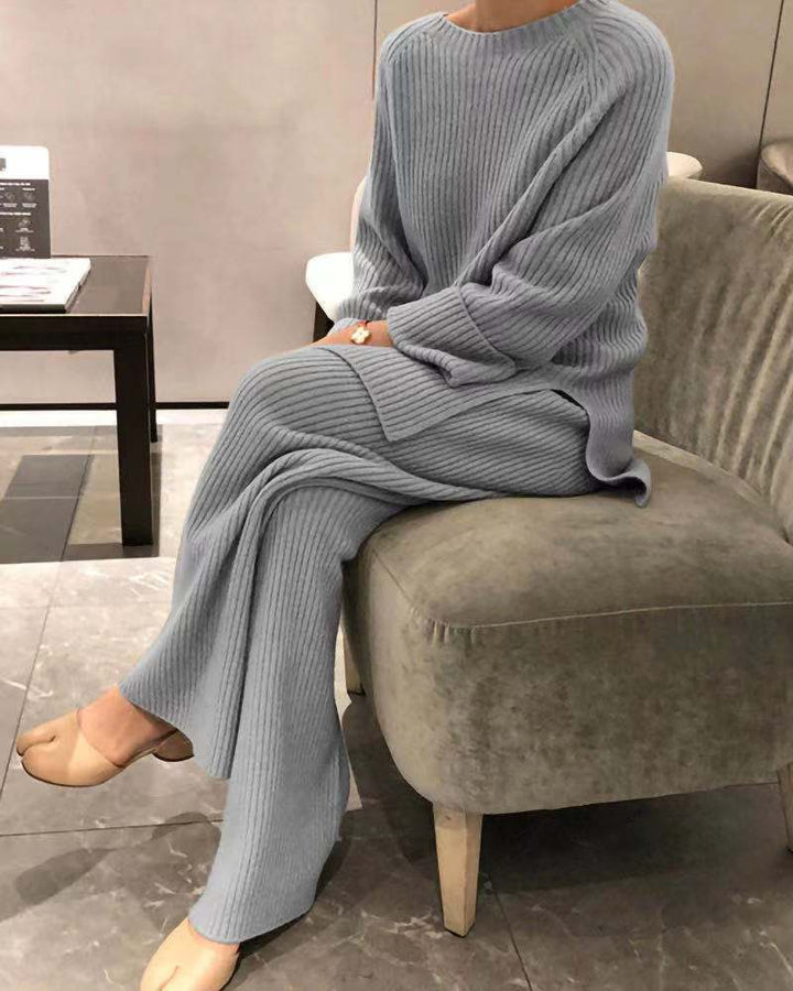 Person wearing a gray knit outfit sitting on a chair indoors.