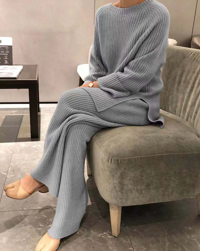 Person wearing a gray knit outfit sitting on a chair indoors.
