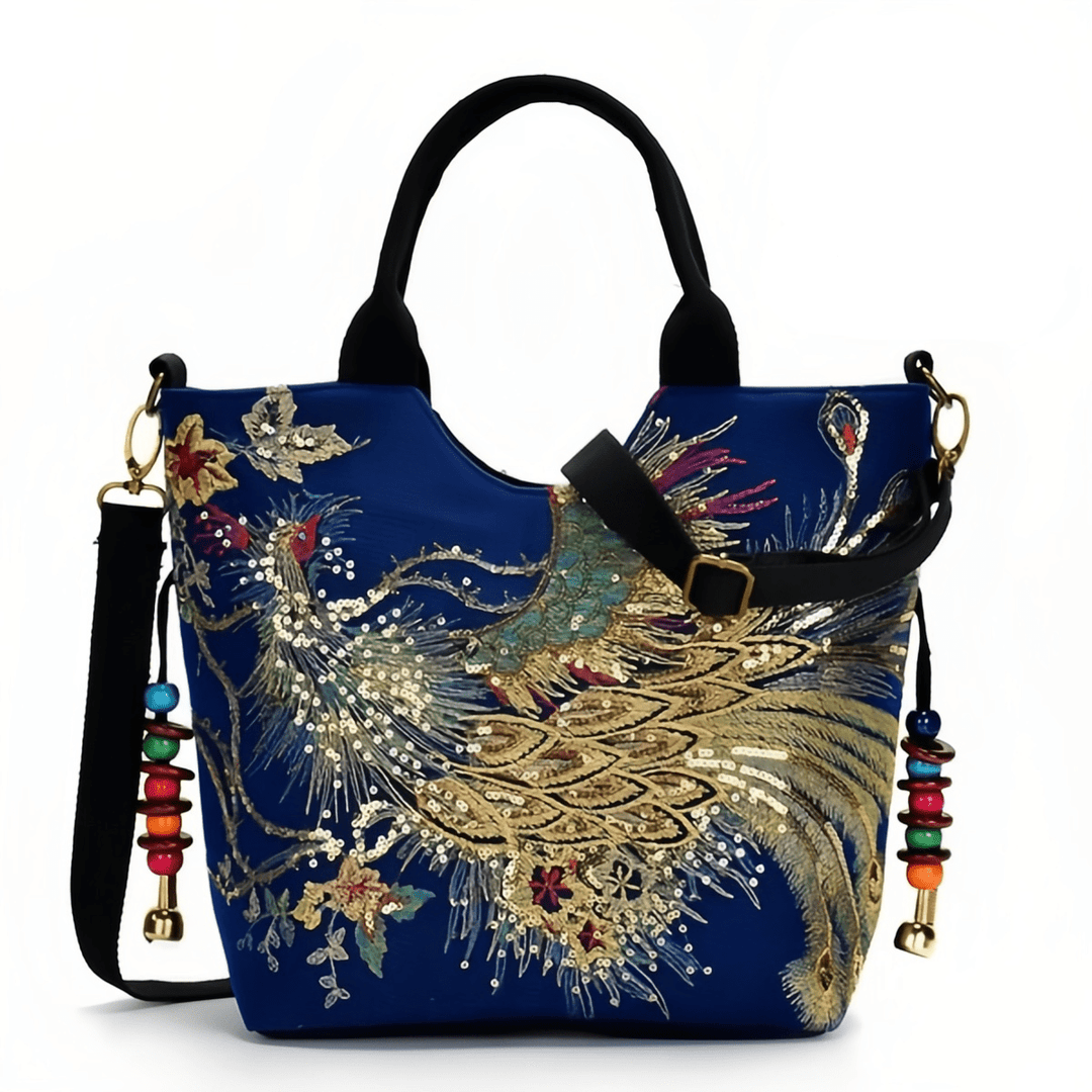 Blue handbag with gold peacock embroidery and colorful tassels on a white background