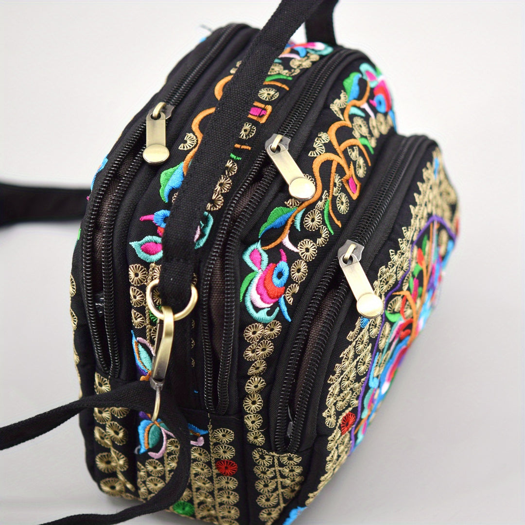 Black handbag with colorful embroidery and gold accents on a white background