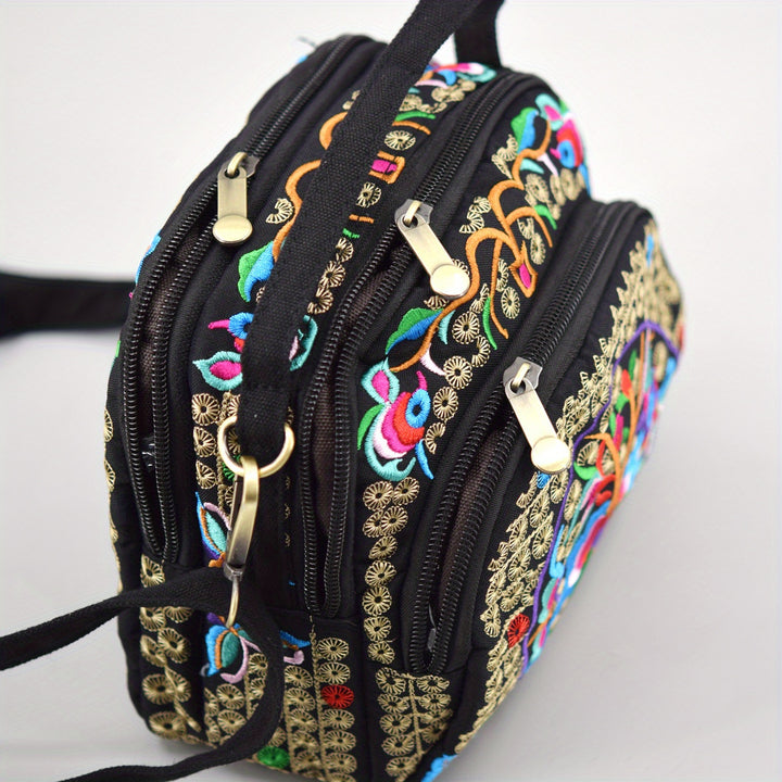 Black handbag with colorful embroidery and gold accents on a white background