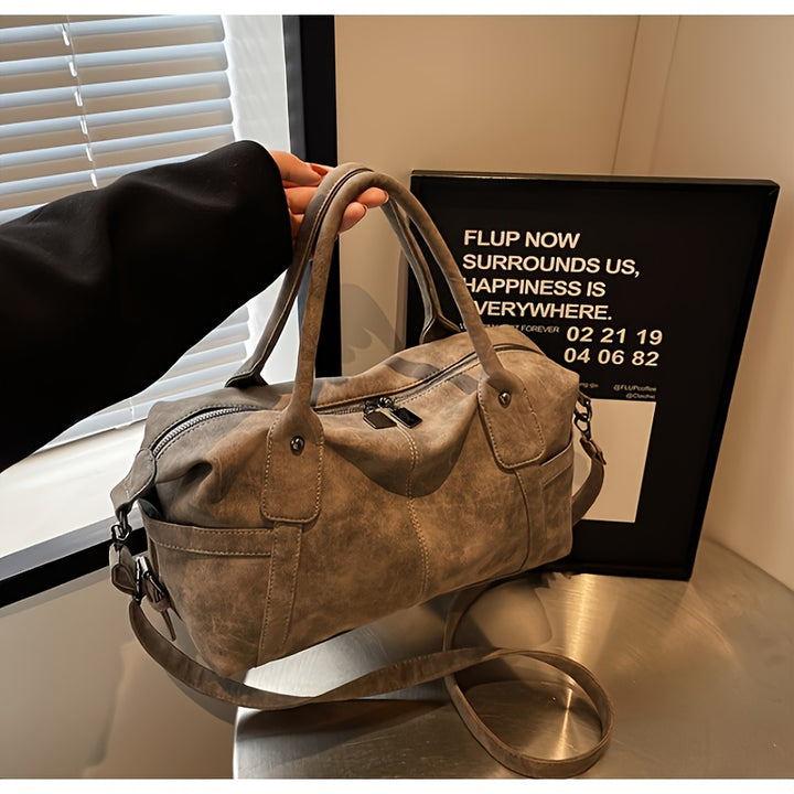 Brown leather handbag on a reflective surface with a blurred background