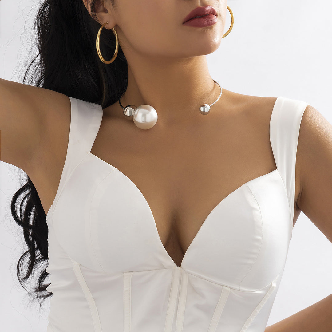 Woman wearing a white dress with a plunging neckline, pearl necklace, and hoop earrings.