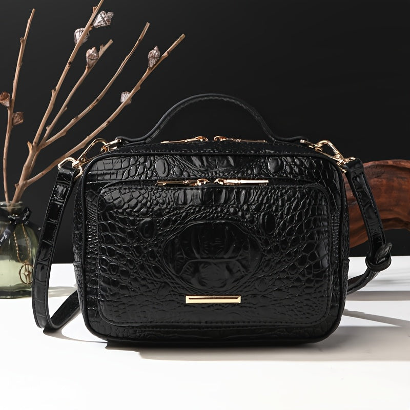 Black crocodile-patterned handbag with gold accents on a dark background