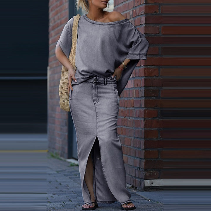 Woman in gray outfit leaning against a brick wall