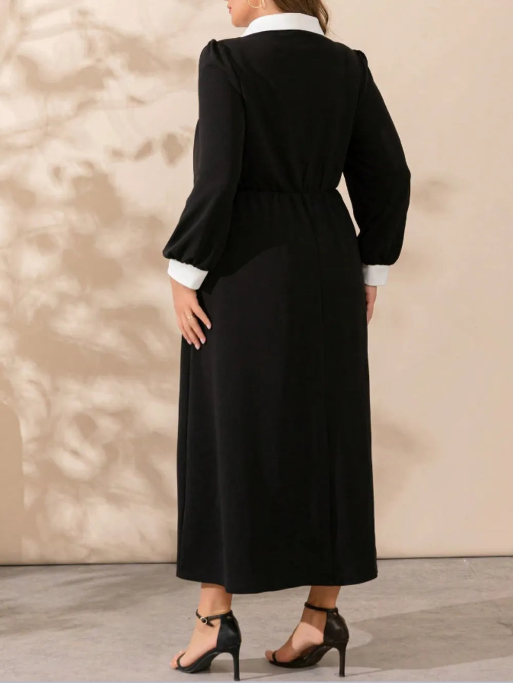 Back view of black long-sleeve midi dress with waist tie and contrast white cuffs