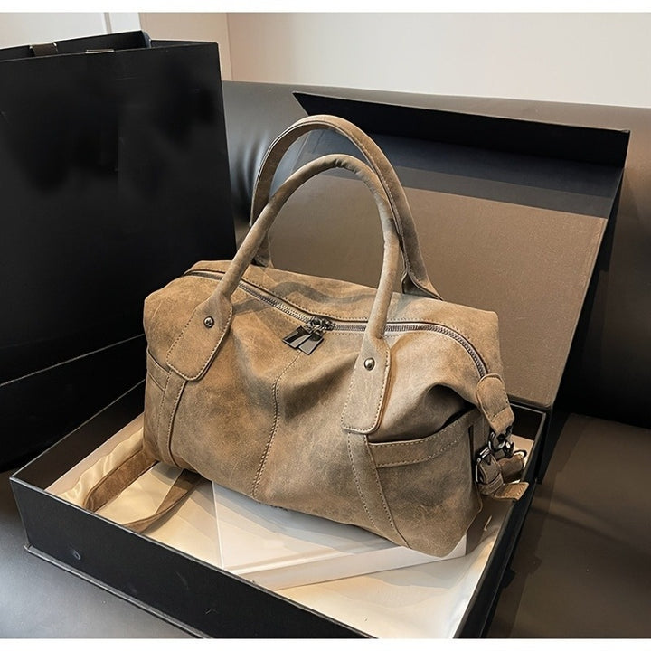 Brown suede handbag in a black box on a gray surface