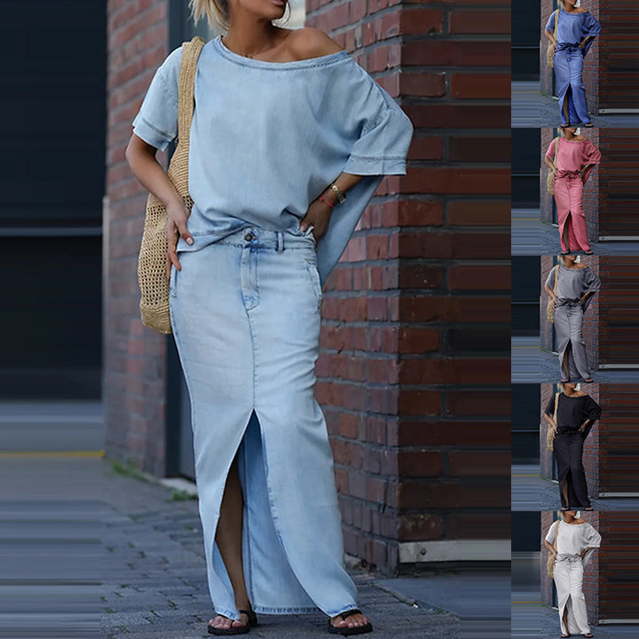 Woman wearing a light blue outfit with a denim skirt against a brick wall.