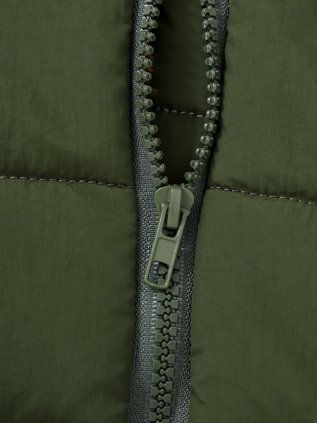 Close-up of a green jacket zipper on a green background
