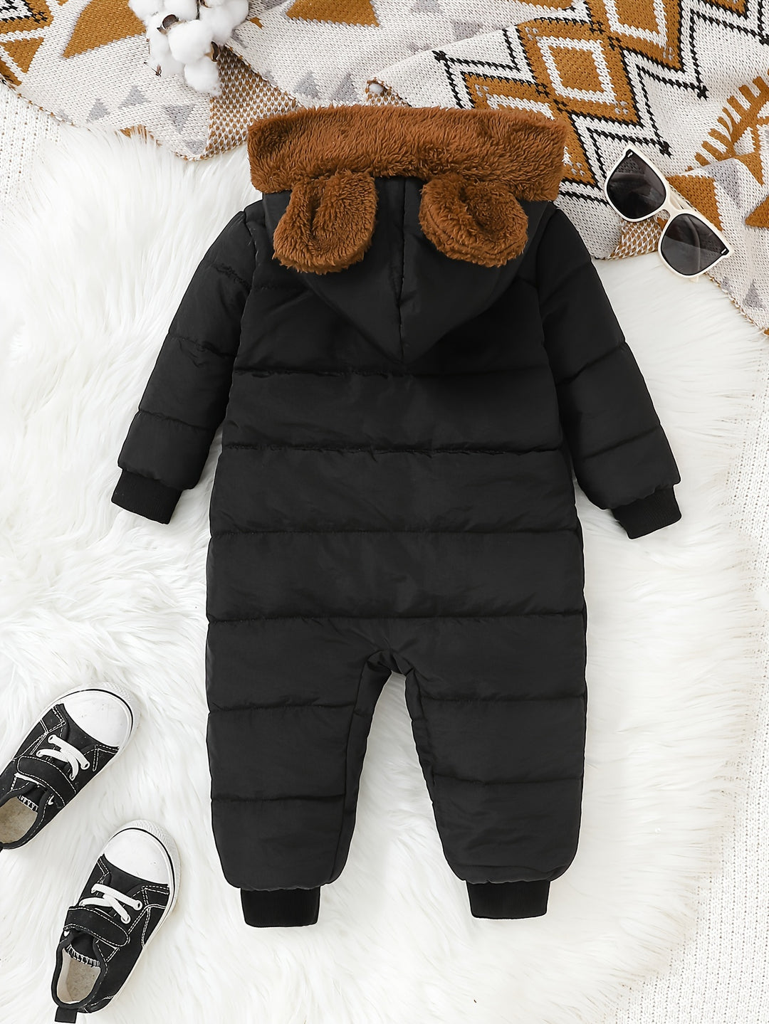 Black puffer snowsuit with brown fur hood on a white surface