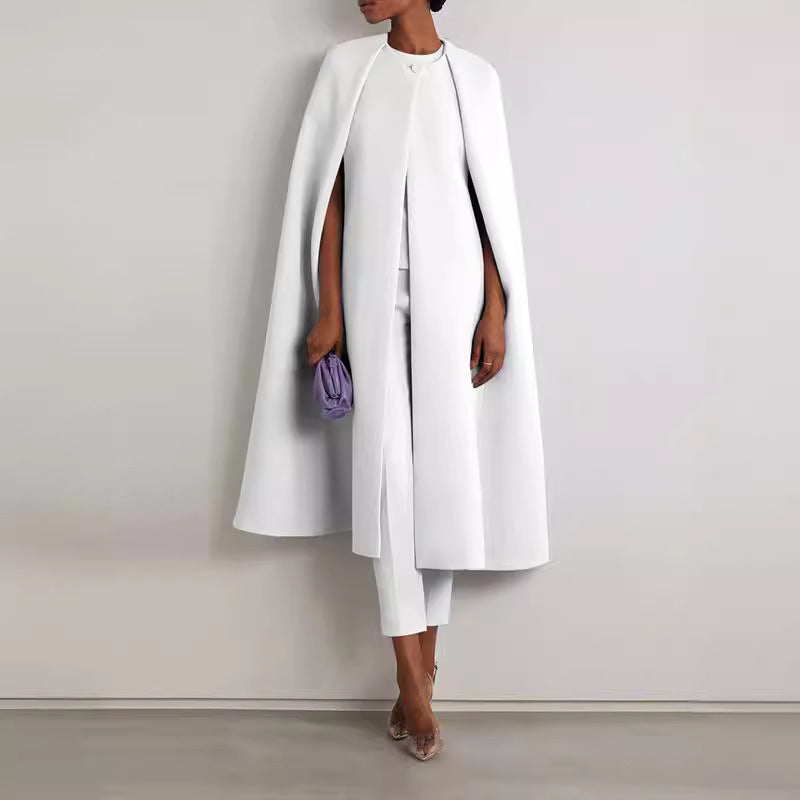 Person wearing a long white coat and white pants against a plain background