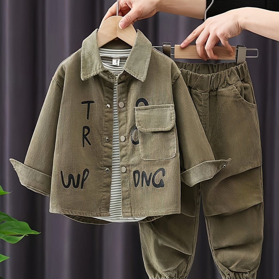 Children's green corduroy jacket and pants set on hangers against a dark background