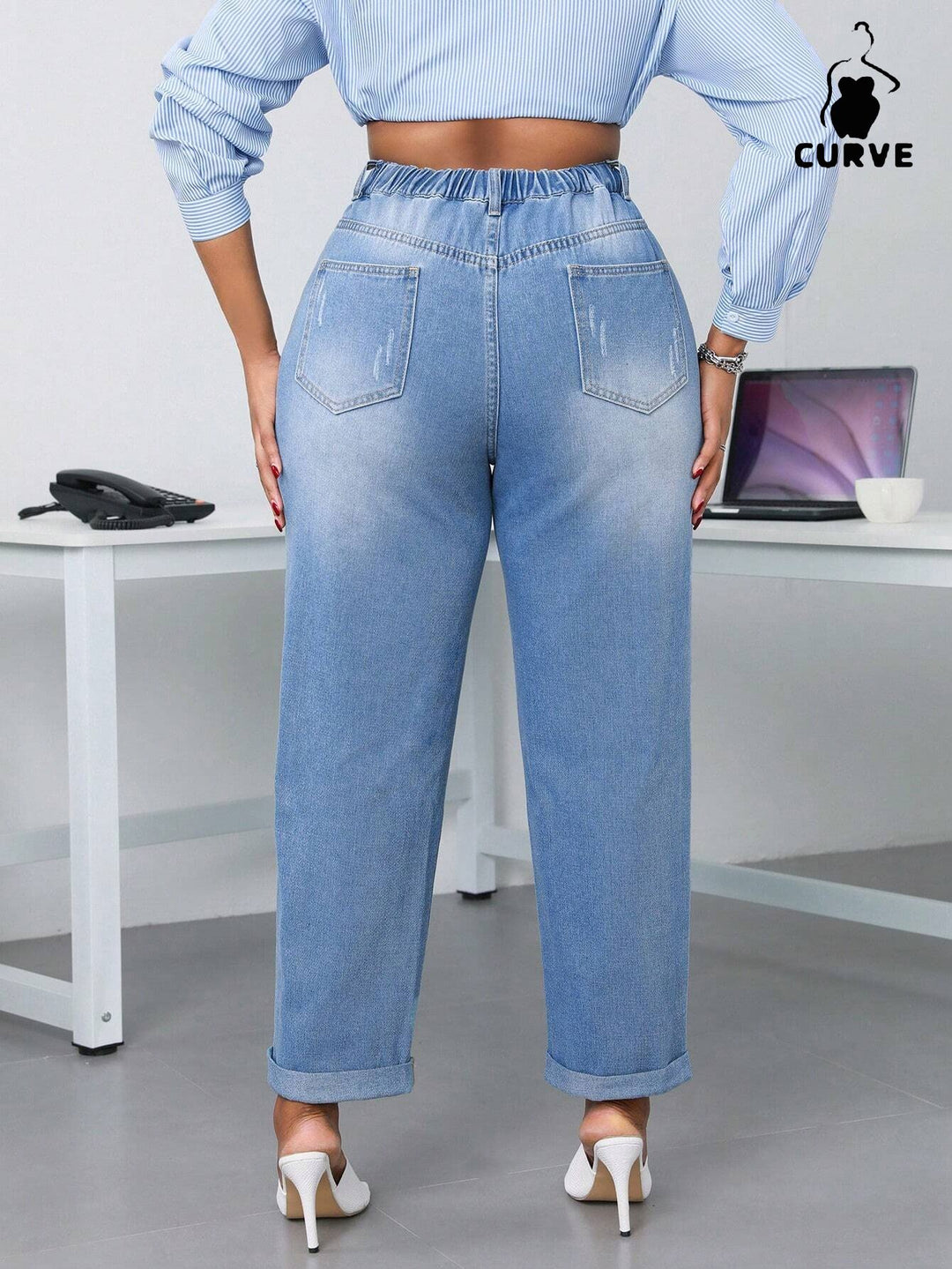 Person wearing light blue jeans and a matching top in an office setting with 'Curve' branding.