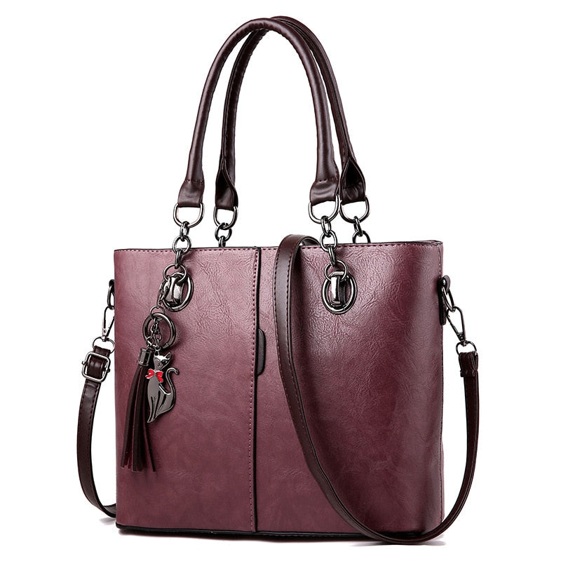 Plum leather tote bag, structured, top handles, crossbody strap, tassel charm