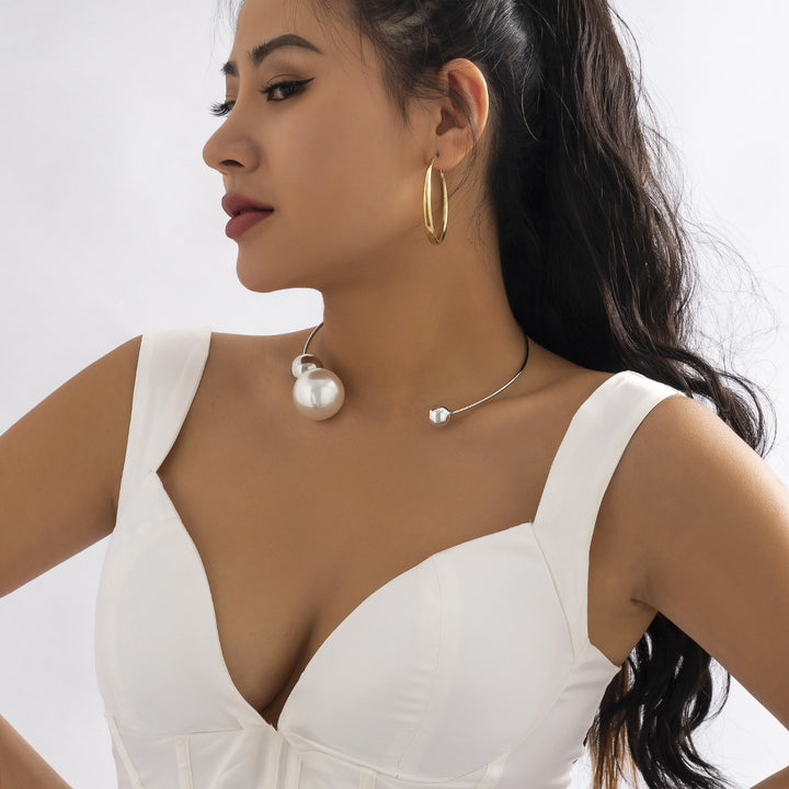 Woman wearing gold hoop earrings and pearl necklace on a white background