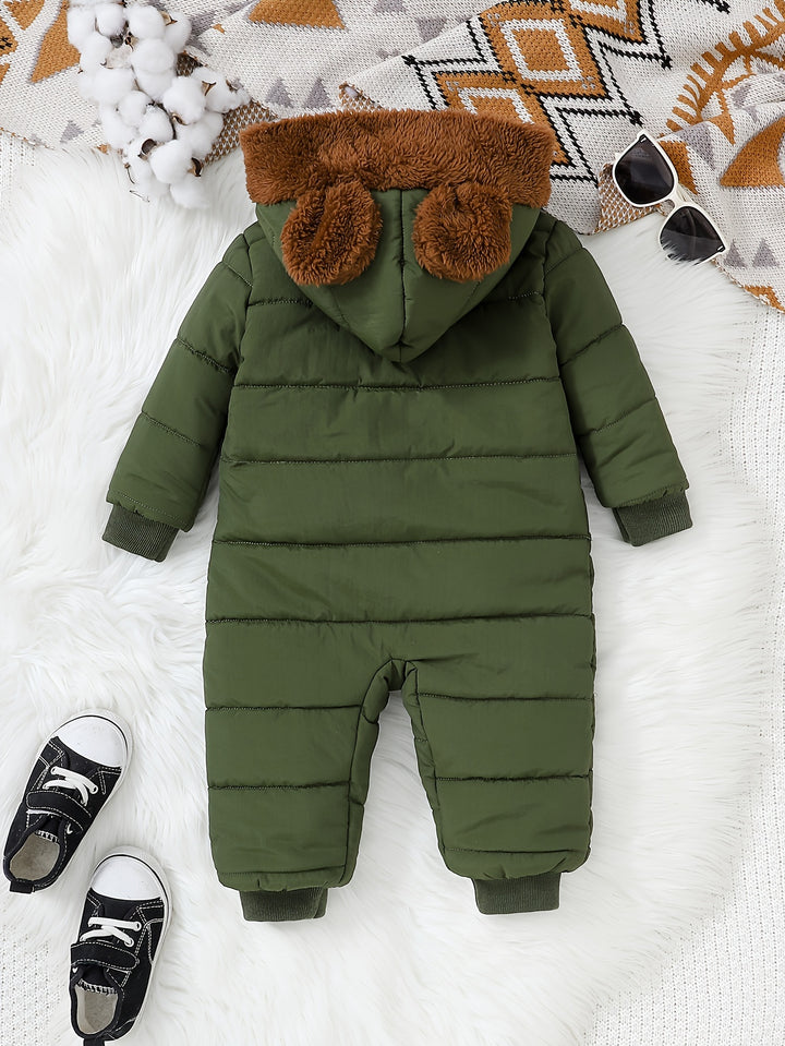 Green baby snowsuit with brown fur hood on a white blanket with shoes and sunglasses.