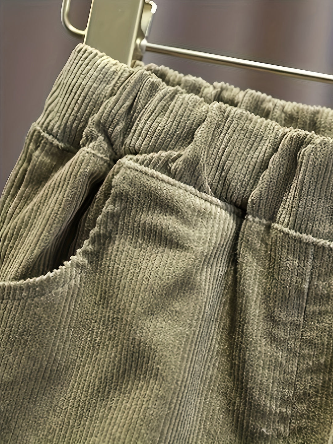 Close-up of green corduroy pants on a hanger with a blurred background