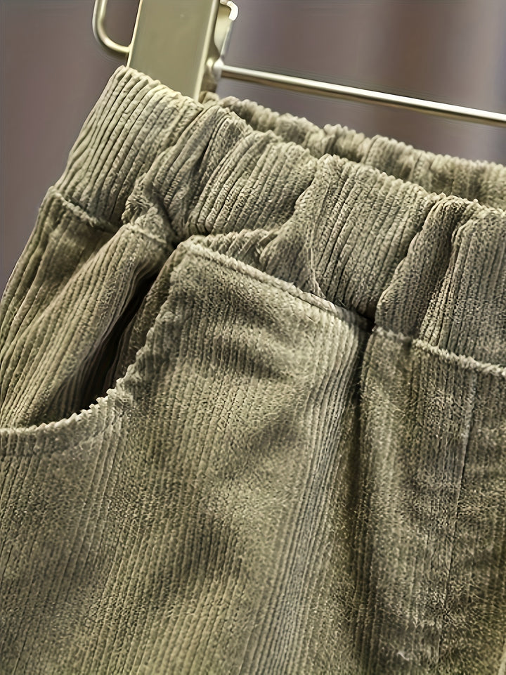Close-up of green corduroy pants on a hanger with a blurred background