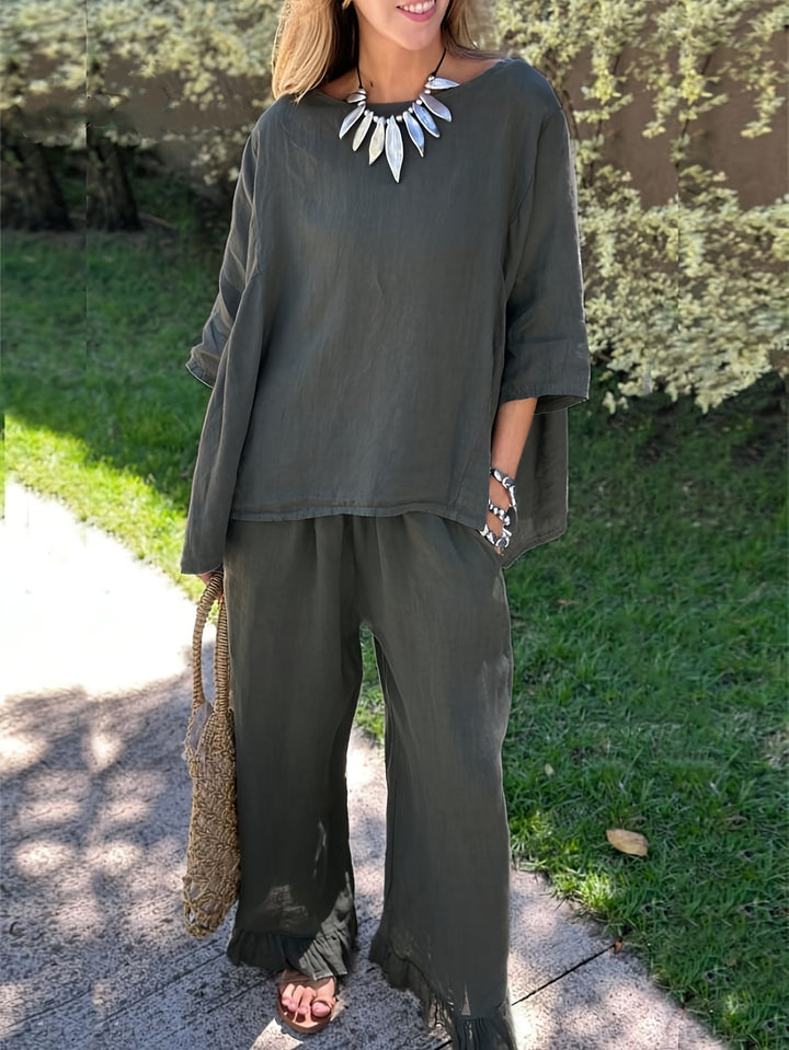 Woman wearing a green outfit with a necklace, standing outdoors on a sunny day.