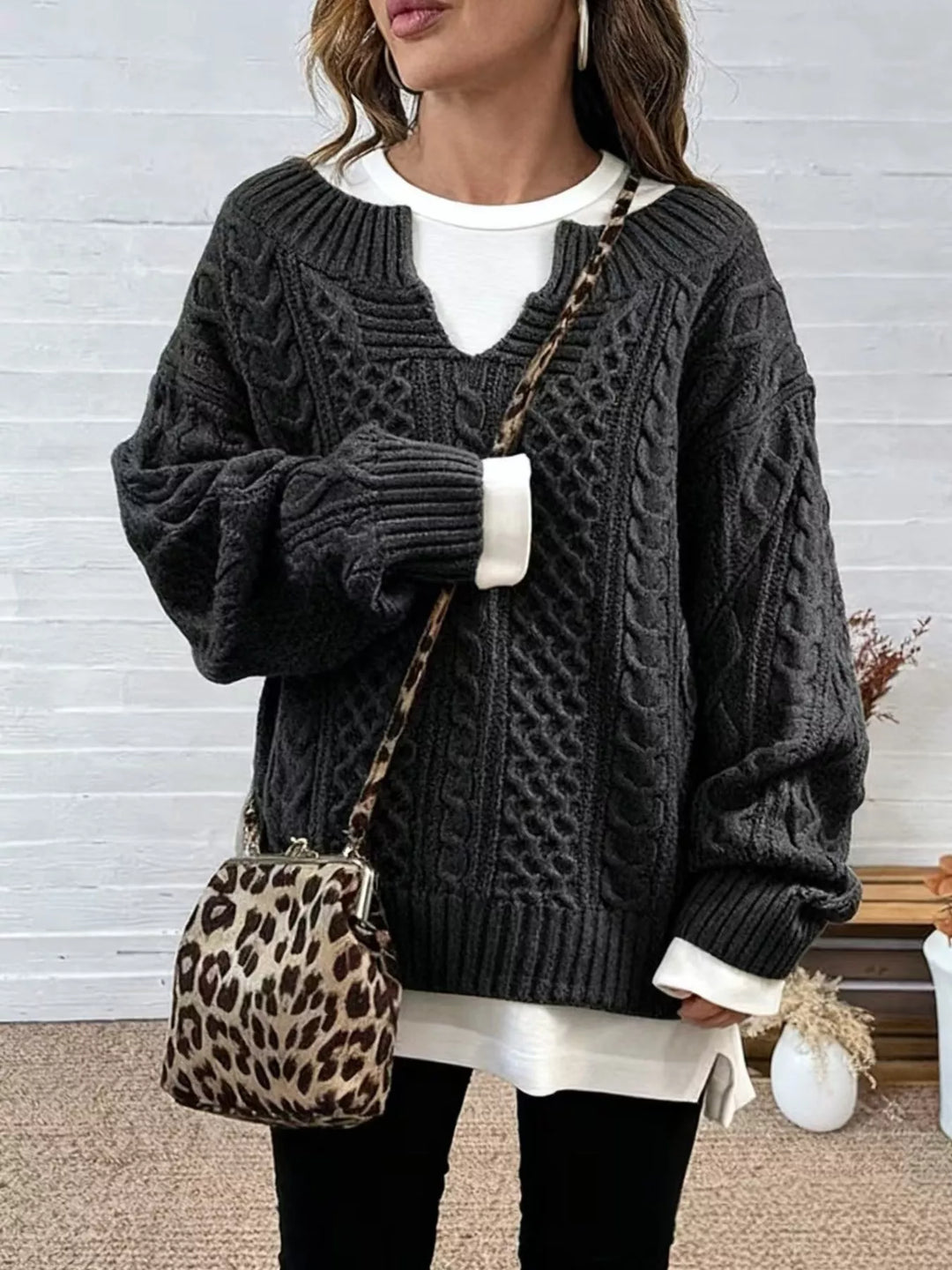 Dark gray cable-knit V-neck sweater with dropped shoulders and ribbed cuffs