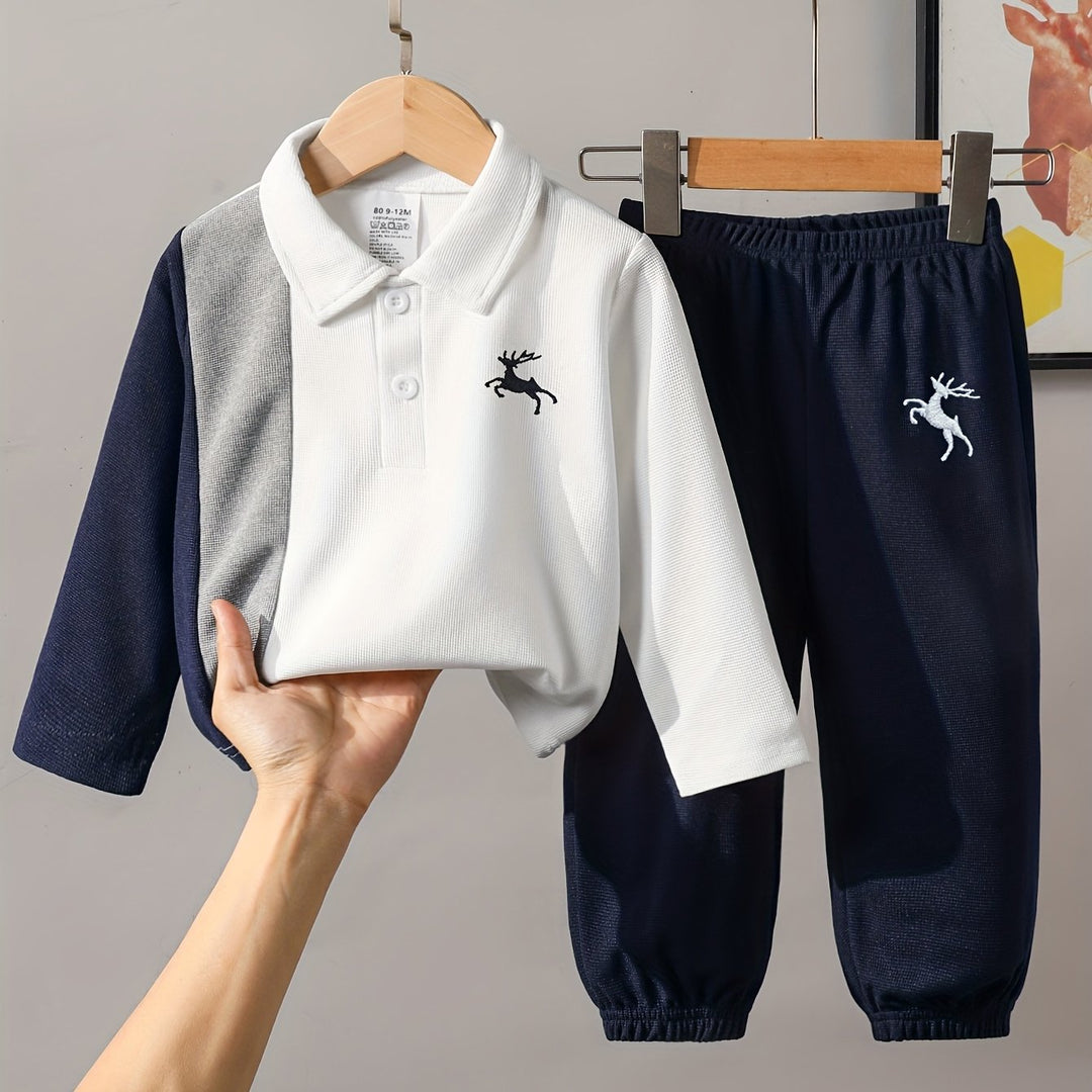Children's outfit with white shirt and navy pants on a hanger against a neutral background