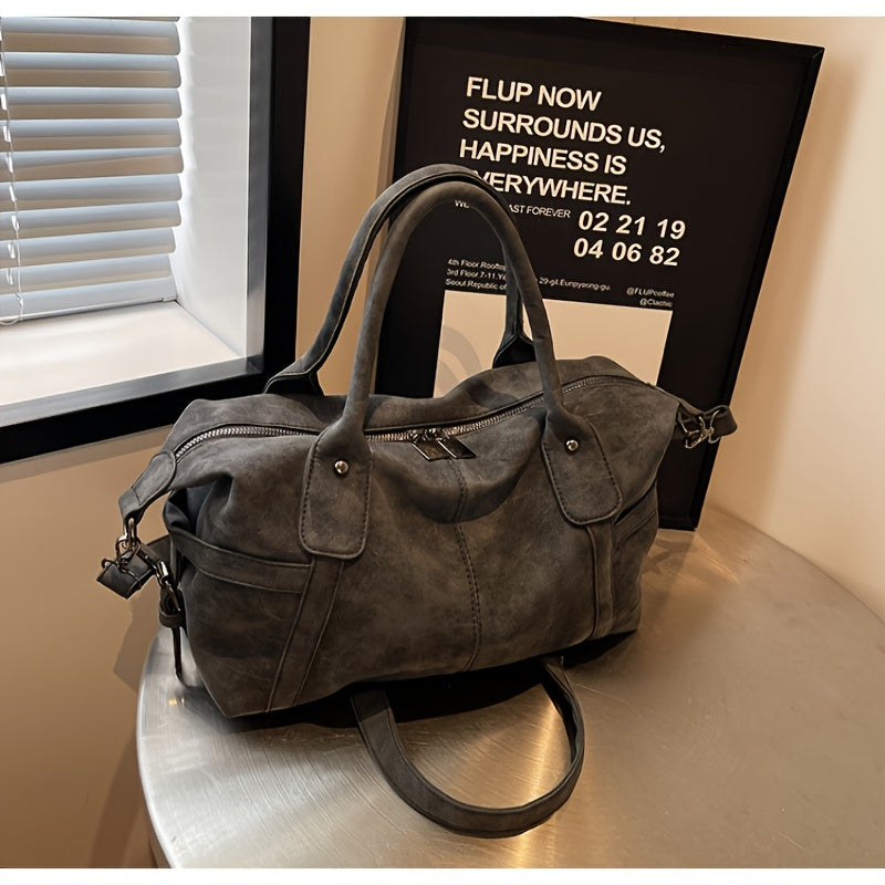 Gray handbag on a reflective surface with a motivational poster in the background