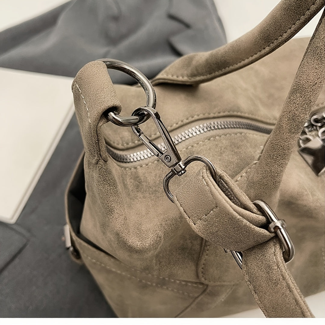 Close-up of a beige handbag with a metal clasp on a neutral background
