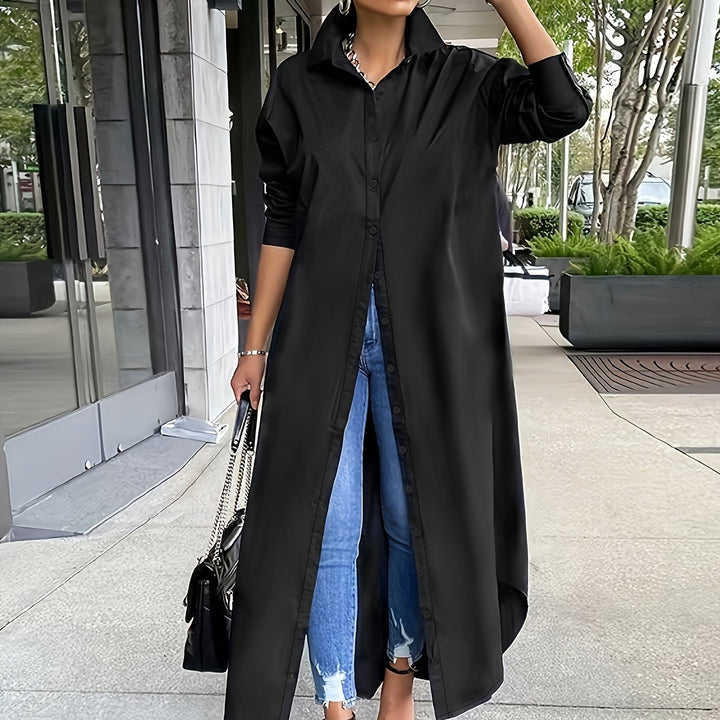 Person wearing a long black coat over blue jeans on a city street.