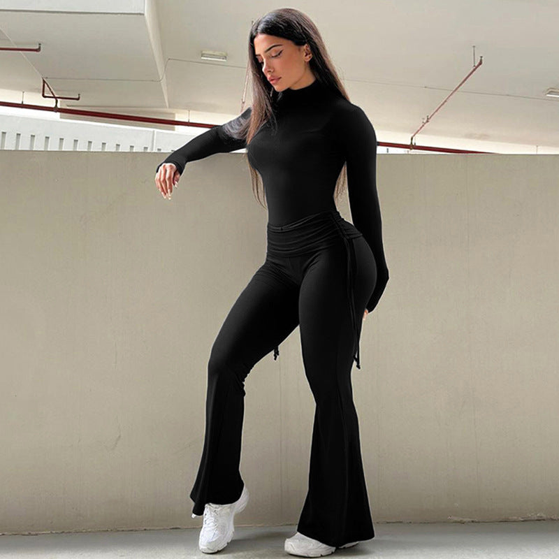 Woman wearing black 2pcs Yoga Set on gray wall.