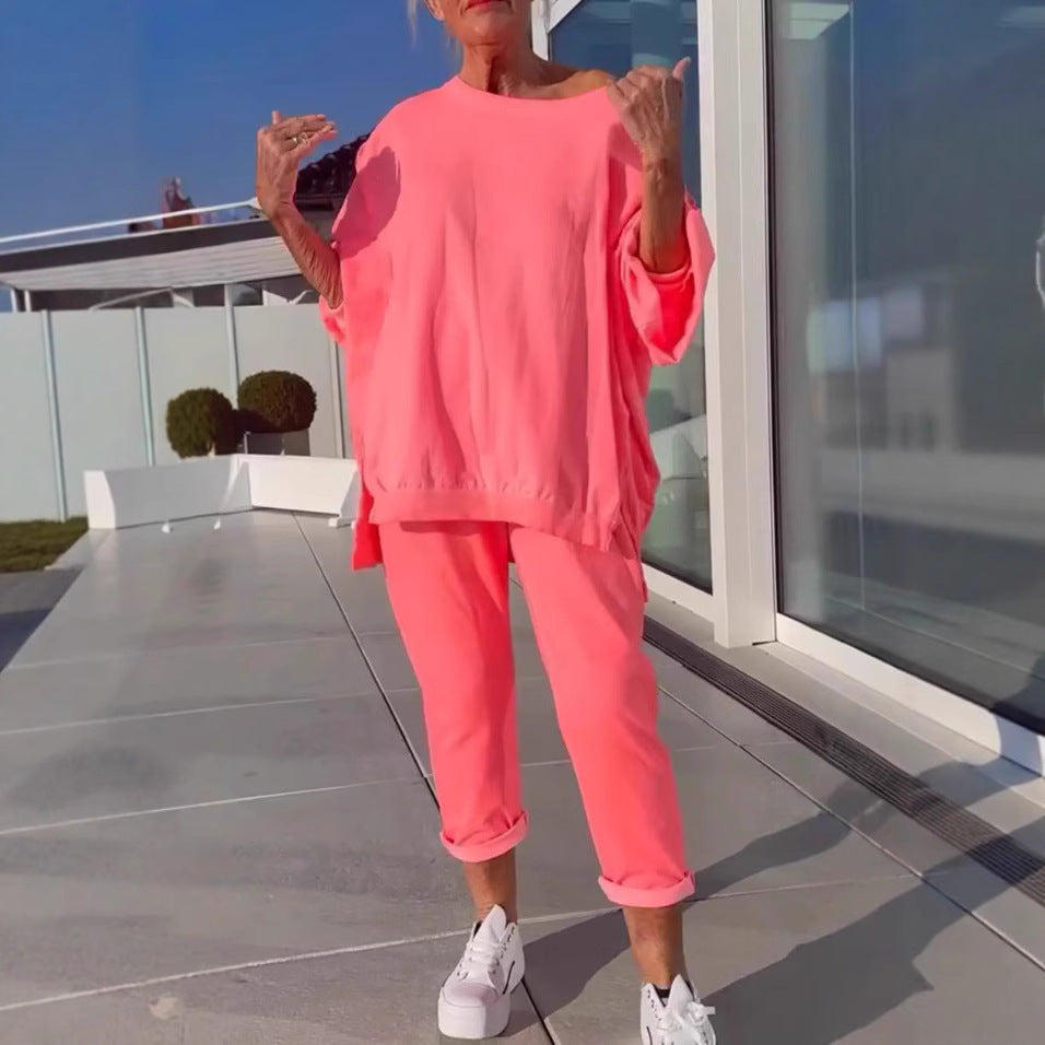 Person wearing a bright pink outfit with white sneakers on a rooftop.