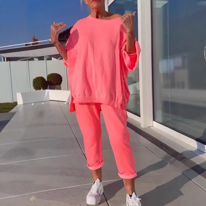 Person wearing a bright pink outfit with white sneakers on a rooftop.