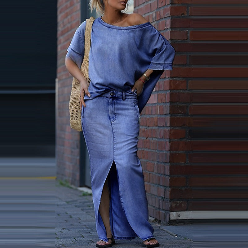 Woman in a blue outfit leaning against a brick wall.