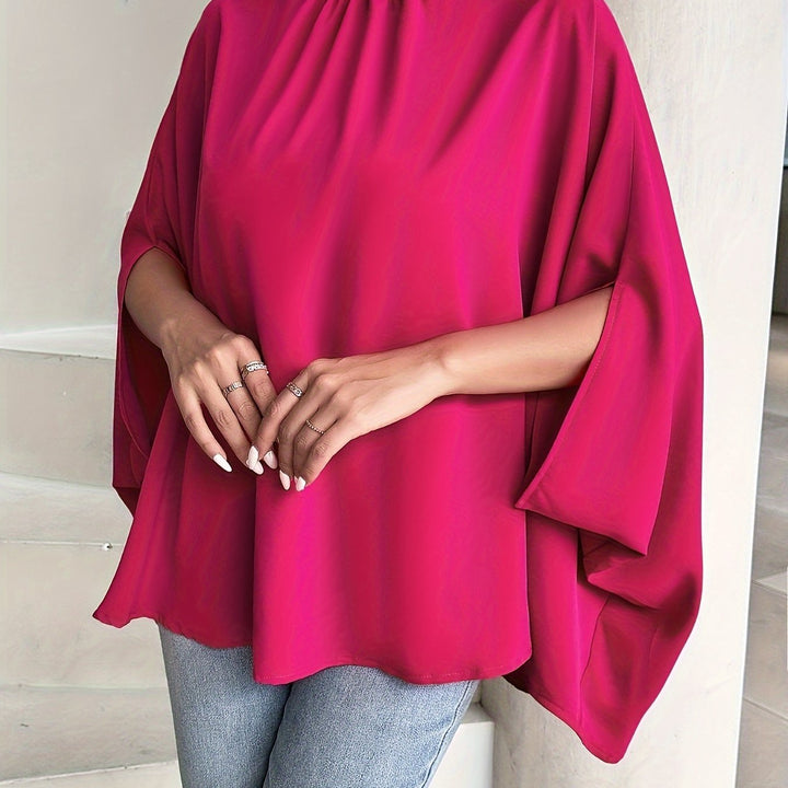 Person wearing a bright pink poncho with a neutral background