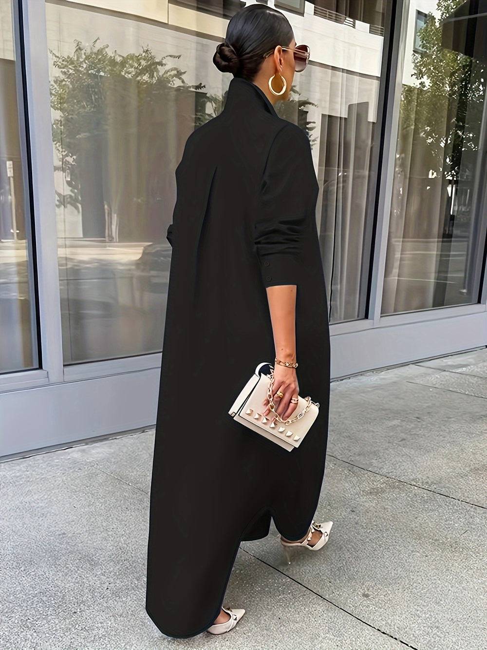 Person wearing a black outfit with a white handbag in an urban setting