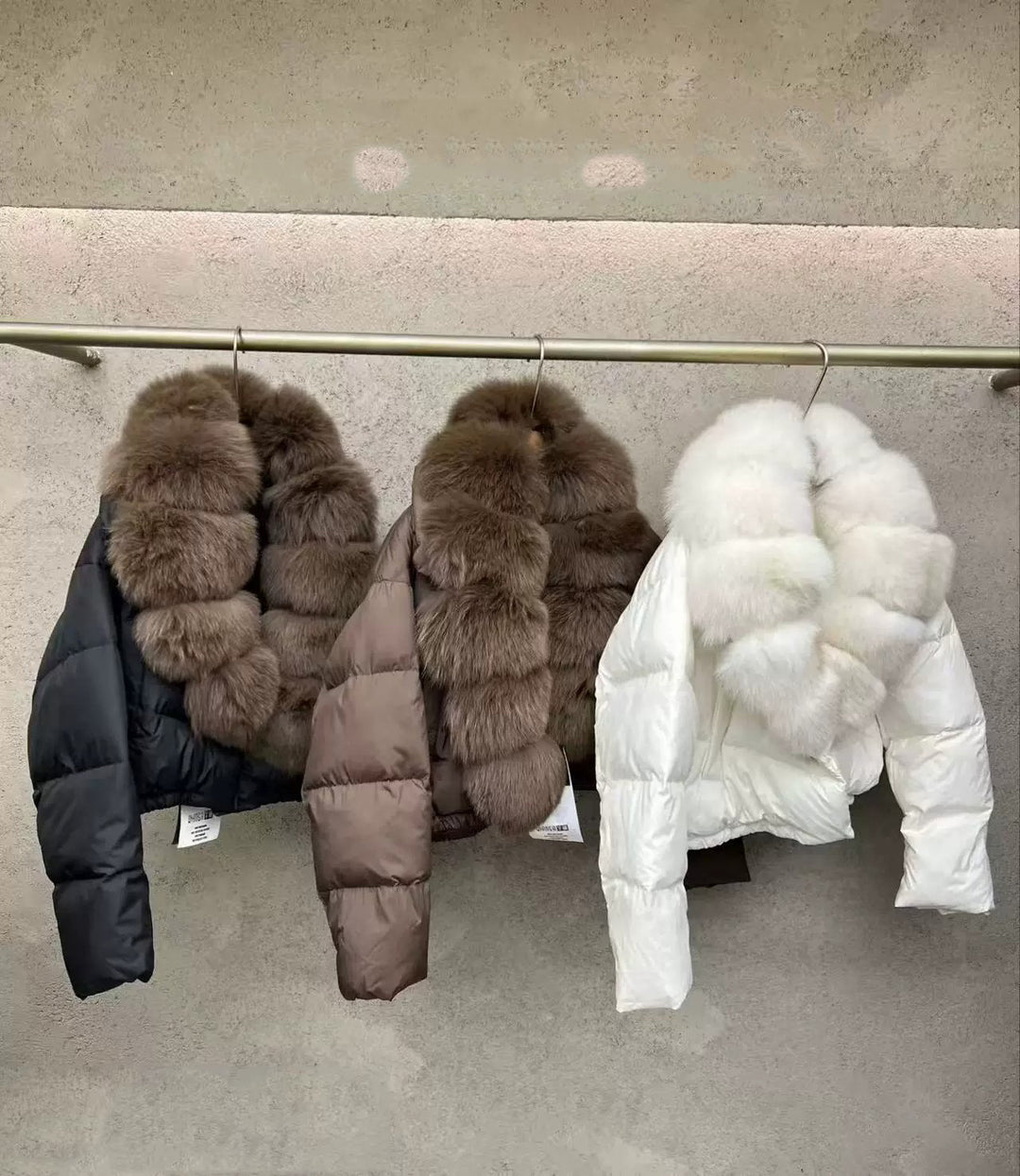 Black, Brown And White Women's Fur Collar Puffer Coats Hanging Side By Side