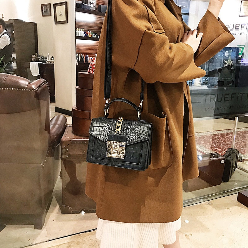 Black crocodile-texture handbag with short chain strap and front flap, gold turn-lock clasp