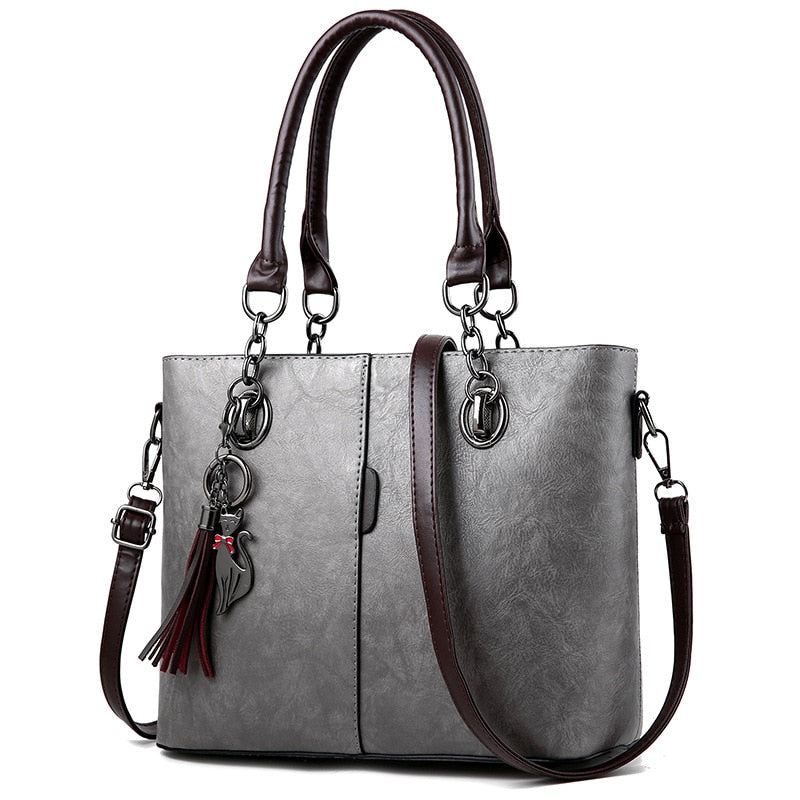 Gray leather tote bag, structured, top handles, crossbody strap, tassel charm