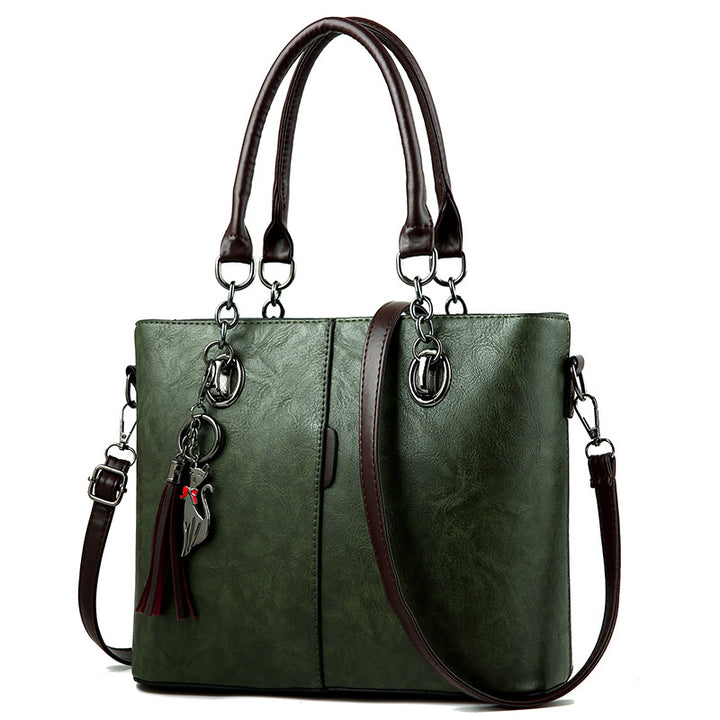 Green leather tote bag, structured, top handles, crossbody strap, tassel charm