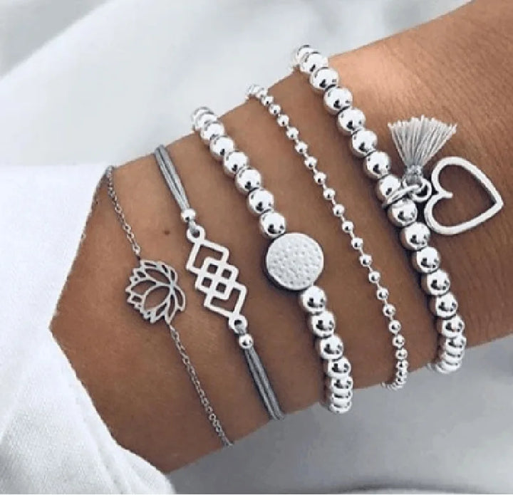 Silver-tone beaded charm bracelet set with leaf, heart outline, and tassel accents