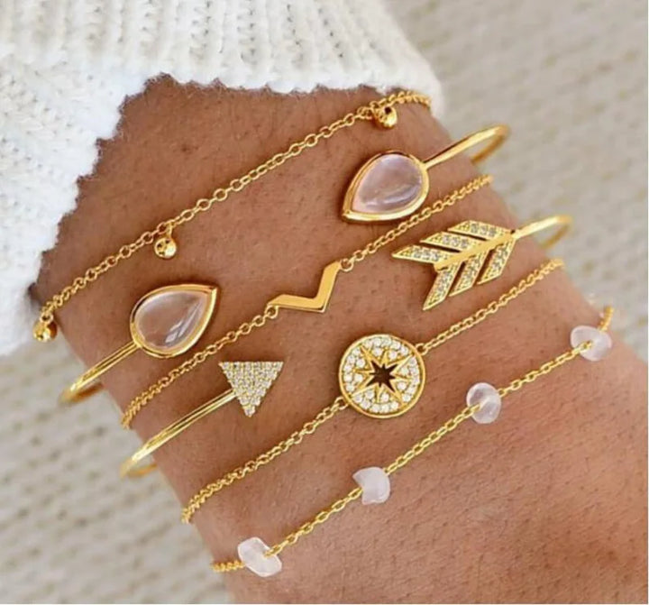 Gold-tone charm bangle bracelet set with heart, triangle, star, and rose-pink stone details