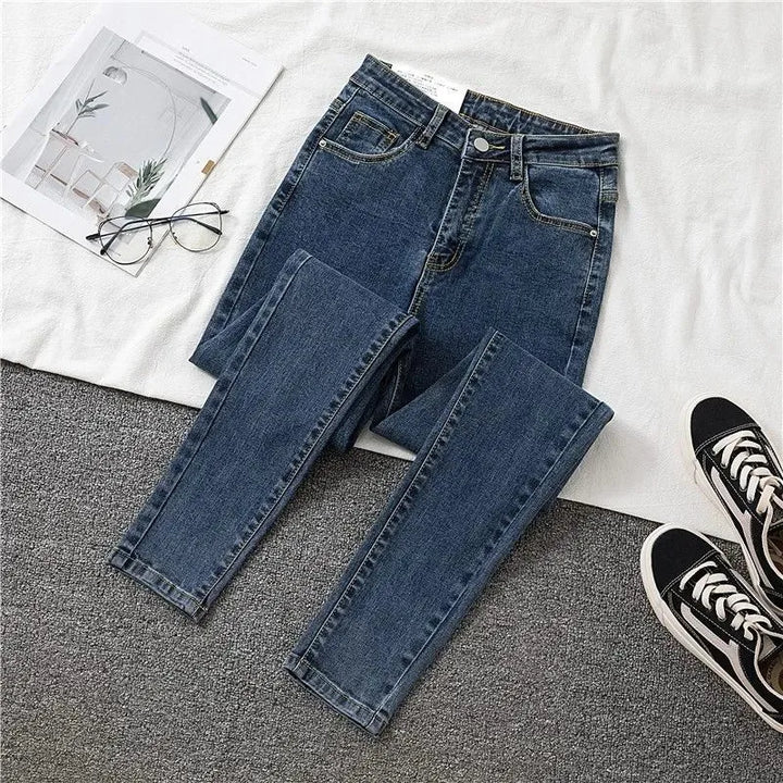 Blue jeans on a textured surface with a magazine and sneakers in the background