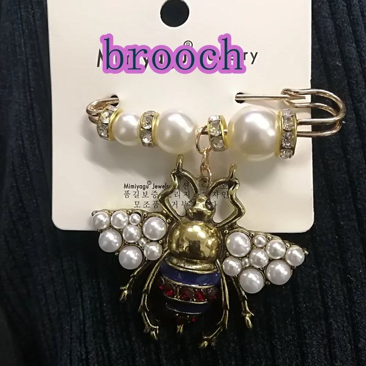 Pearl and gold bee-shaped brooch on a card with 'brooch' text.