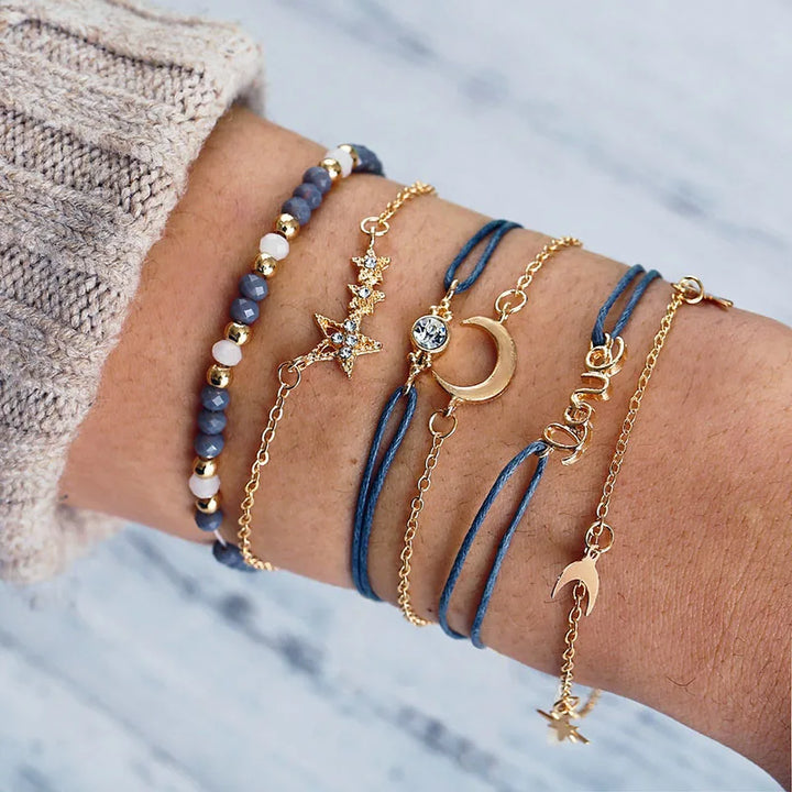 Stacked charm bracelets with blue beaded bands, star and crescent pendants, and gold-tone links